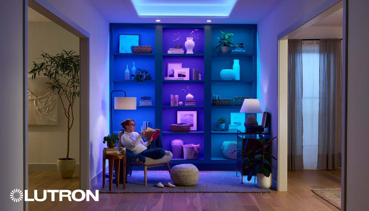 A person sitting in front of a book case with lights on it.