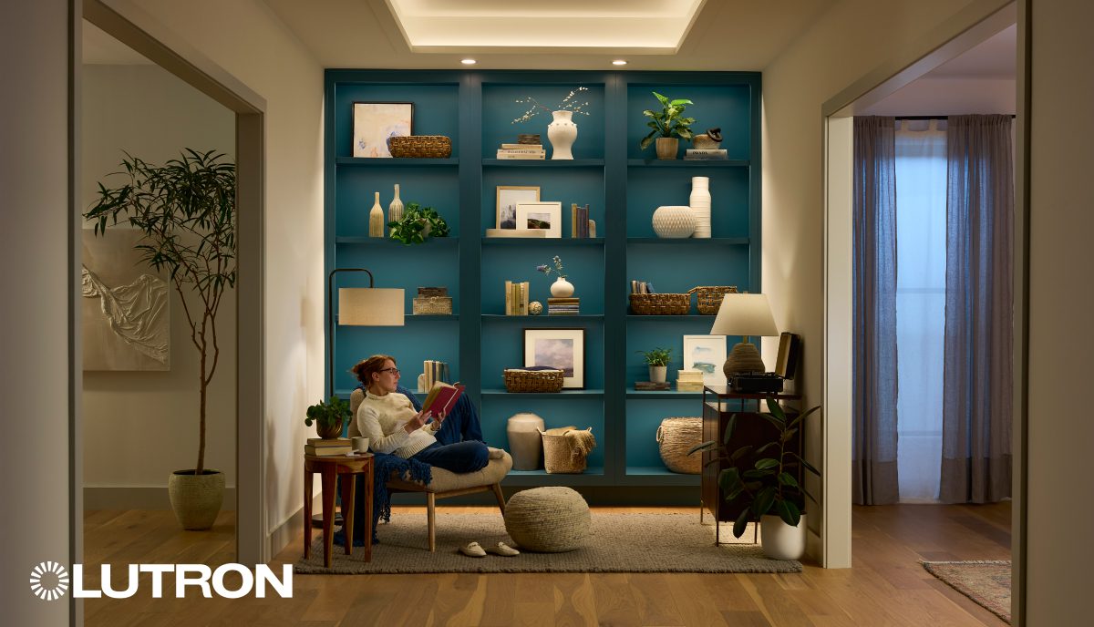 A man sitting on the floor in front of a bookshelf.